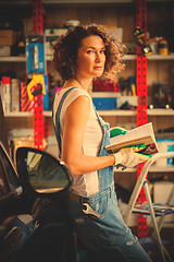 Image showing woman mechanic with a wrench and repair manual in his hand