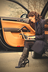 Image showing Work on the road. woman in a dark coat with a laptop