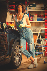 Image showing pretty woman mechanic in blue denim overalls studies repair guid