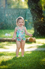 Image showing The little baby girl playing with garden sprinkler.