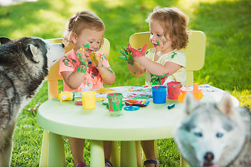 Image showing Two-year old girls painting with poster paintings together against green lawn