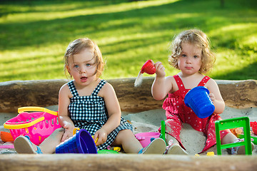 Image showing The two little baby girls playing toys in sand