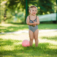 Image showing The little baby girl playing with garden sprinkler.