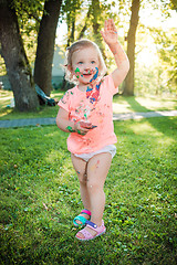 Image showing Two-year old girl stained in colors against green lawn