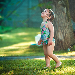 Image showing The little baby girl playing with garden sprinkler.