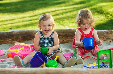 Image showing The two little baby girls playing toys in sand