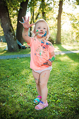 Image showing Two-year old girl stained in colors against green lawn