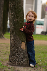 Image showing Small beauty girl playing hide-and-seek at the park.