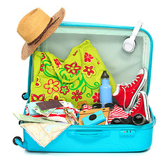 Image showing The open blue suitcase, sneakers, clothing, hat, and retro camera on white background.