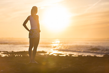 Image showing Woman on sandy beach watching sunset.