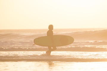 Image showing Silhouette of surfer on beach with surfboard.