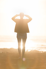 Image showing Woman on sandy beach watching sunset.