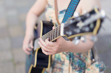 Image showing Female street musician playing guitar.