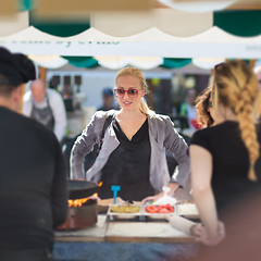 Image showing Woman buying meal at street food festival.