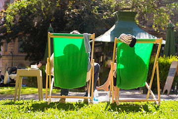 Image showing Silhouette of relaxed couple on deckchairs in a park