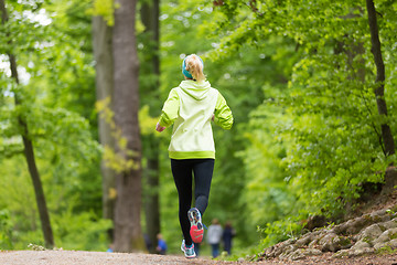 Image showing Sporty young female runner in the forest. 