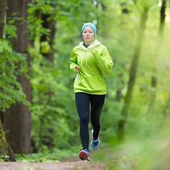 Image showing Sporty young female runner in the forest. 