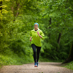 Image showing Sporty young female runner in the forest. 