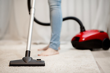 Image showing Woman doing house cleaning, vacuuming carpet with thick pile