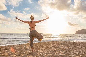 Image showing Woman practicing yoga on sea beach at sunset.