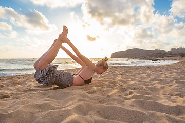 Image showing Woman practicing yoga on sea beach at sunset.