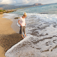 Image showing Woman walking on sand beach at golden hour