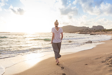 Image showing Woman walking on sand beach at golden hour