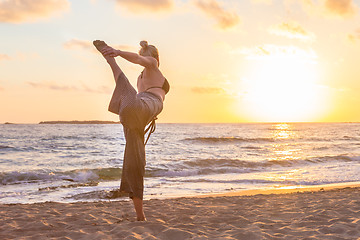 Image showing Woman practicing yoga on sea beach at sunset.