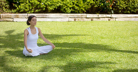 Image showing Lovely young woman meditating in the garden