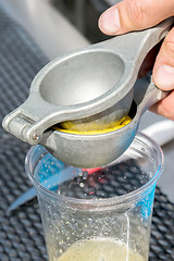 Image showing manual metal juicer lemon in a plastic Cup