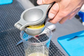 Image showing manual metal juicer lemon in a plastic Cup