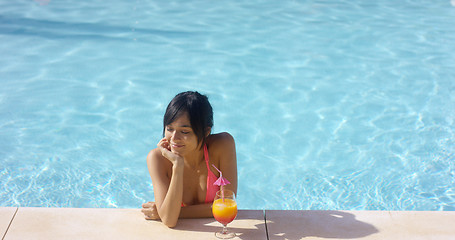 Image showing Contented woman at pool edge with drink