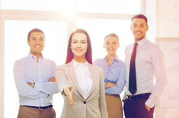 Image showing smiling businesswoman in office with team on back