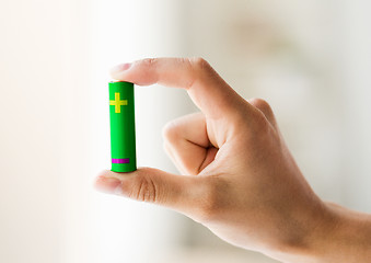 Image showing close up of hand holding green alkaline battery