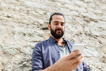 Image showing man texting message on smartphone at stone wall