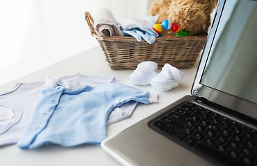 Image showing close up of baby clothes, toys and laptop at home