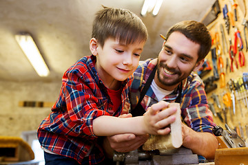 Image showing father and little son with wood plank at workshop