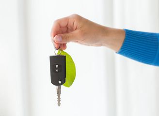 Image showing close up of hand holding car key with green leaf