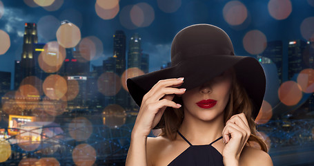Image showing beautiful woman in black hat over night city