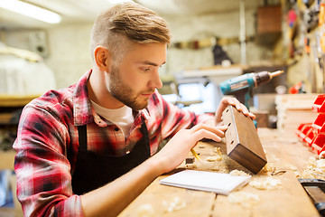 Image showing carpenter working with wood plank at workshop