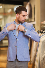 Image showing young man trying jacket on in clothing store