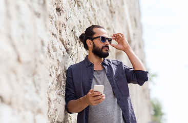 Image showing man with smartphone at stone wall