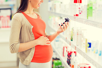 Image showing happy pregnant woman with medication at pharmacy