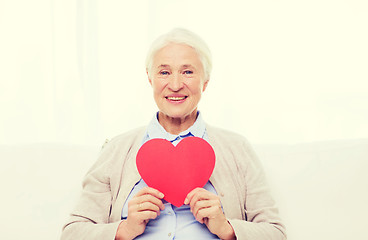 Image showing happy smiling senior woman with red heart at home