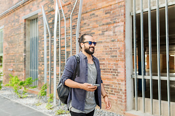 Image showing man with earphones and smartphone walking in city