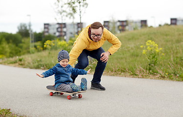 Image showing happy father and little son riding on skateboard