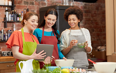 Image showing happy women with tablet pc cooking in kitchen