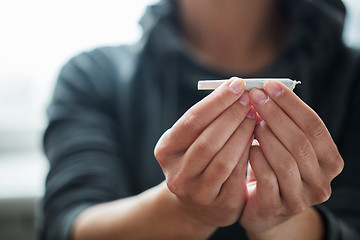 Image showing close up of addict hands with marijuana joint