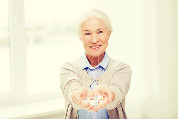 Image showing happy senior woman with medicine at home