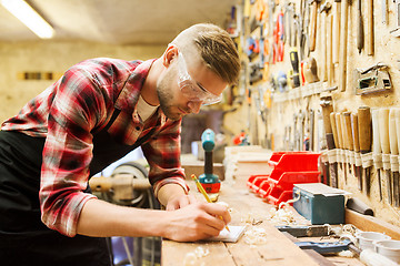 Image showing carpenter writing to notebook at workshop